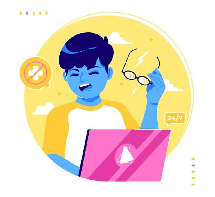 A geek with glasses smiles while using a laptop