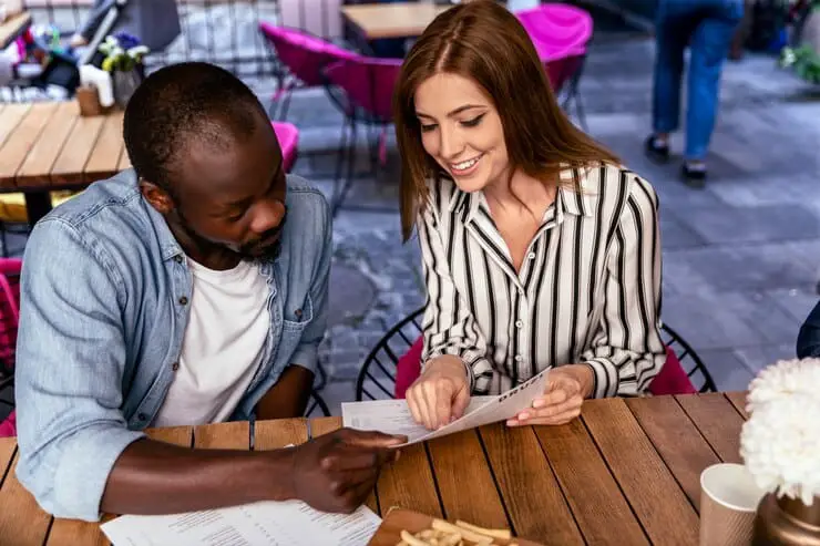 A man and woman are seated at a table, reviewing documents and discussing her simple pleasures response on HInge