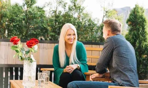 A man and woman engaged in discussion while sitting at a patio table in a relaxed outdoor setting